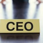 Wooden block with 'CEO' text on a reflective surface.